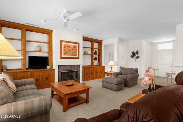 22622 N Mazatlan Dr, Sun City West, AZ 85375 - living area with visible vents, a glass covered fireplace, built in shelves, a ceiling fan, and carpet
