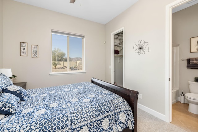 tiled bedroom featuring ceiling fan, ensuite bath, a closet, and a walk in closet