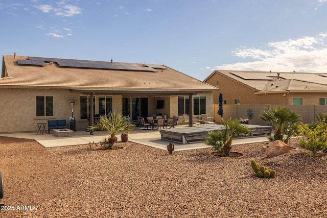 back of property with a patio area, solar panels, and an outdoor fire pit