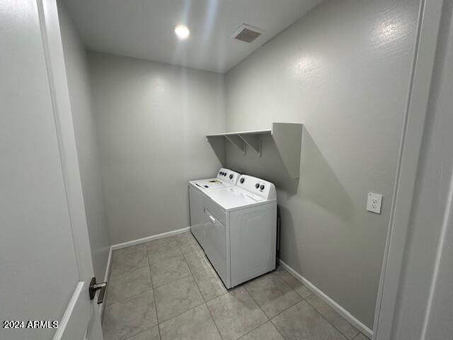 clothes washing area featuring light tile patterned floors and washing machine and clothes dryer