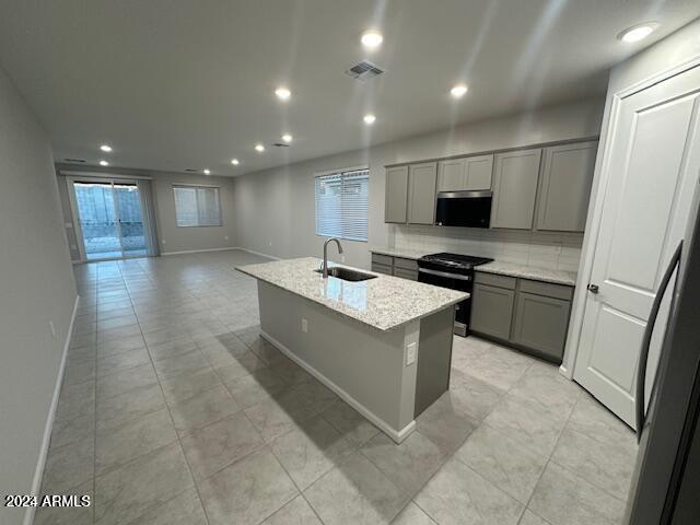 kitchen with a healthy amount of sunlight, sink, stainless steel appliances, and an island with sink