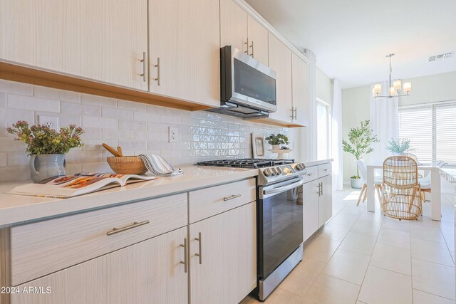 kitchen featuring hanging light fixtures, light tile patterned floors, tasteful backsplash, stainless steel appliances, and a chandelier