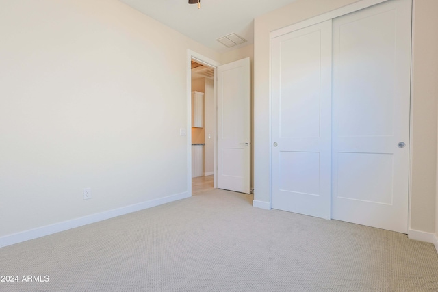 unfurnished bedroom with light colored carpet and a closet