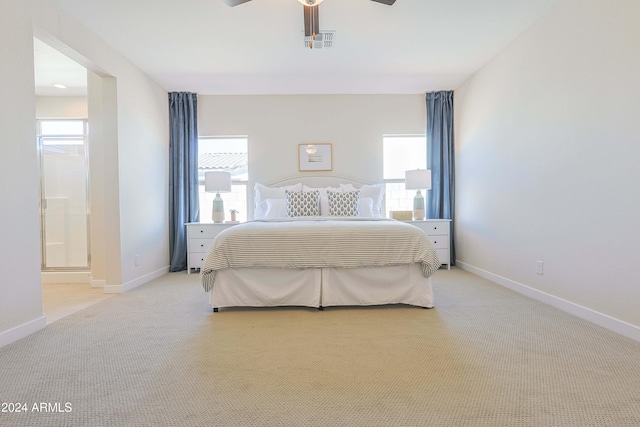 bedroom featuring ensuite bath, ceiling fan, light colored carpet, and multiple windows