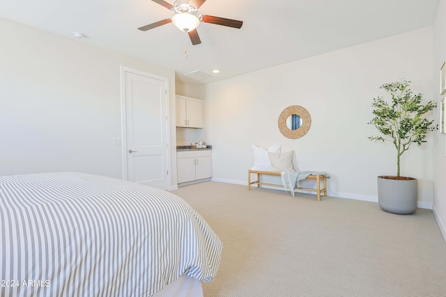 bedroom featuring connected bathroom, light carpet, and ceiling fan