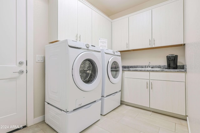 laundry area with cabinets, light tile patterned floors, washing machine and dryer, and sink