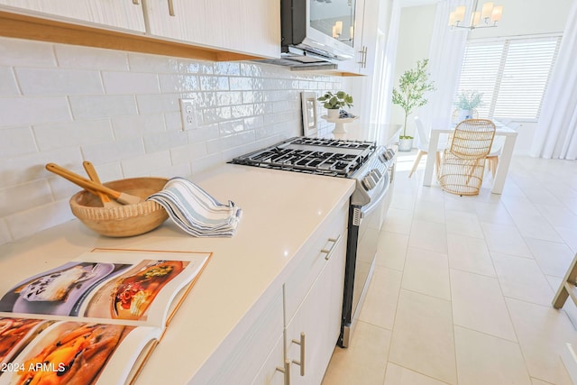 kitchen with decorative backsplash, appliances with stainless steel finishes, white cabinets, and hanging light fixtures