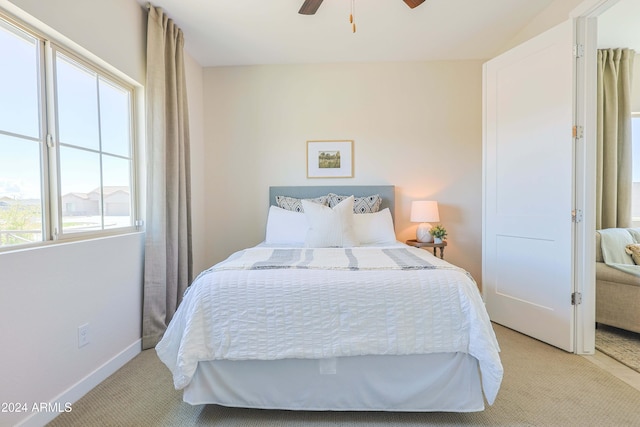 bedroom with multiple windows, ceiling fan, and light carpet