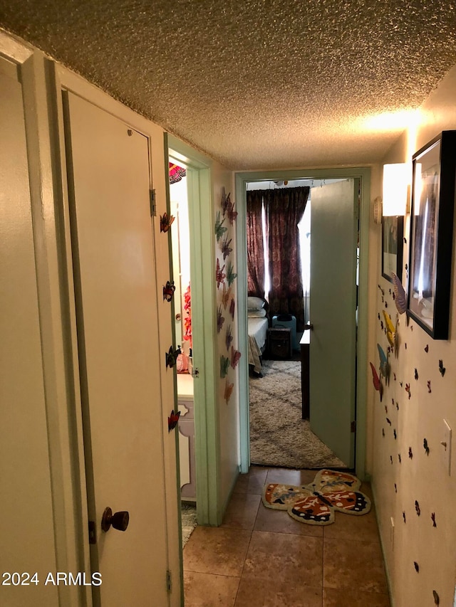 corridor with a textured ceiling and tile patterned flooring