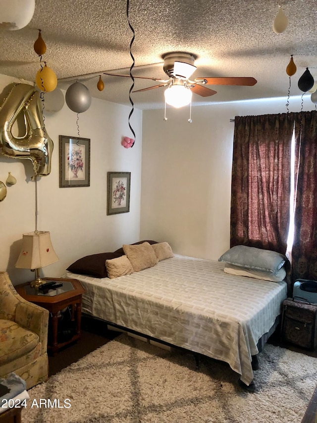 carpeted bedroom with ceiling fan and a textured ceiling