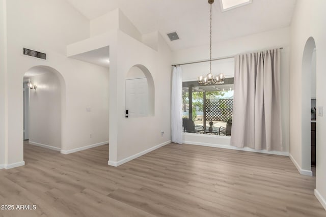 12529 N 83rd Ln, Peoria, AZ 85381 - unfurnished dining area featuring arched walkways, light wood-type flooring, baseboards, and high vaulted ceiling