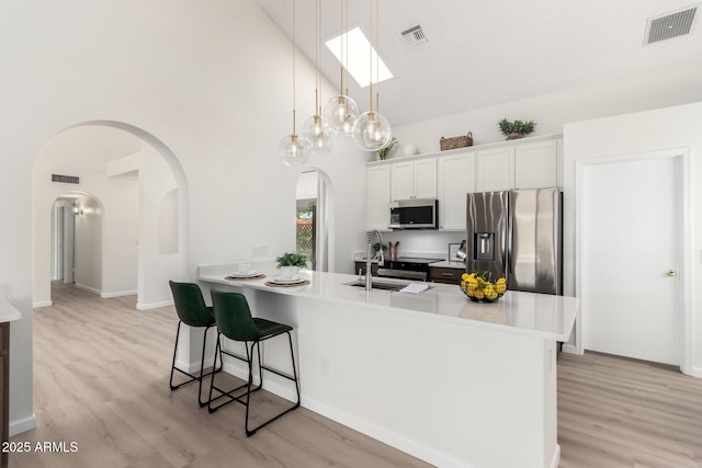 12529 N 83rd Ln, Peoria, AZ 85381 - kitchen with stainless steel appliances, a sink, high vaulted ceiling, arched walkways, and a breakfast bar area