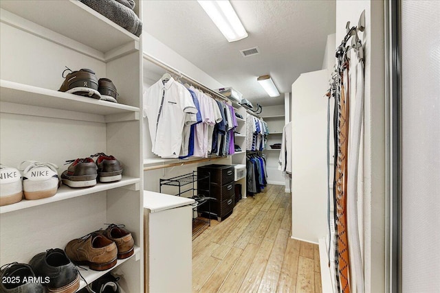 walk in closet with light hardwood / wood-style flooring