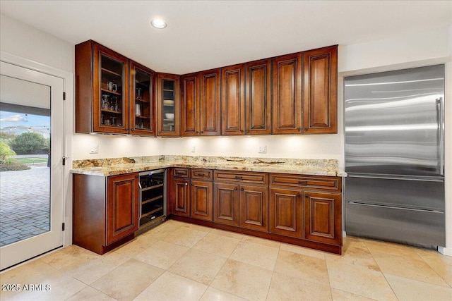 kitchen with stainless steel built in refrigerator, light stone countertops, and beverage cooler