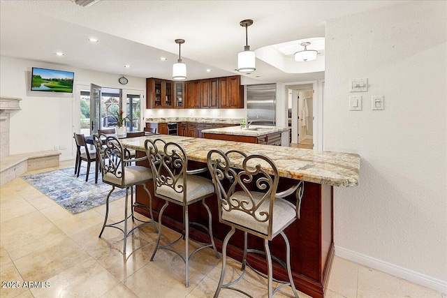 kitchen featuring a breakfast bar, sink, built in refrigerator, decorative light fixtures, and kitchen peninsula