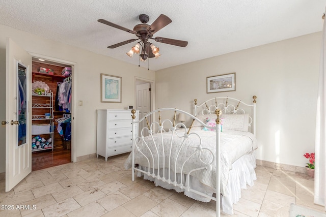 bedroom with ceiling fan, a closet, a spacious closet, and a textured ceiling