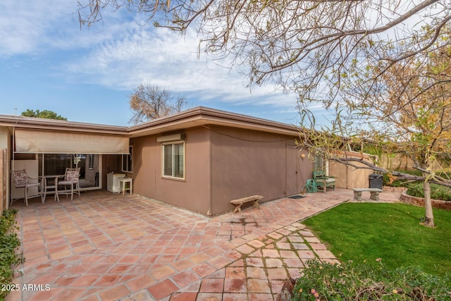 back of property with a yard and a patio