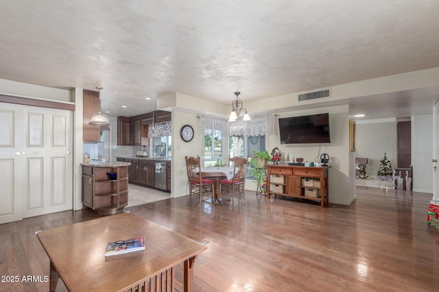 living room with wood-type flooring, an inviting chandelier, and sink