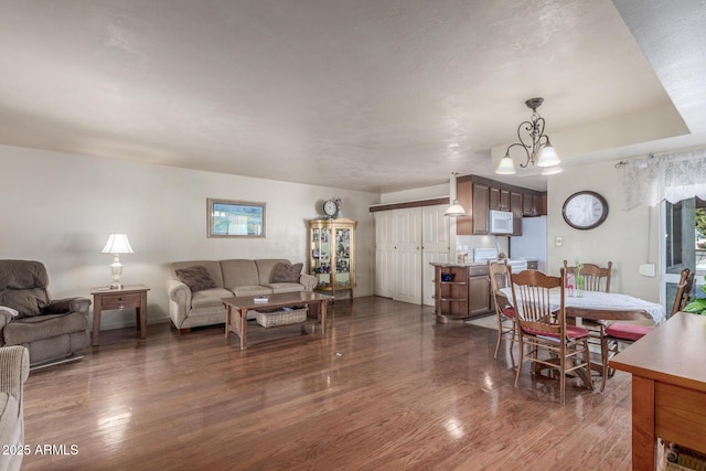 living room featuring dark hardwood / wood-style flooring, a healthy amount of sunlight, and an inviting chandelier