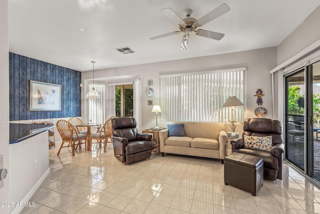 living room with light tile patterned flooring and ceiling fan with notable chandelier