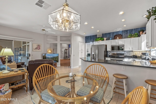 dining area featuring ceiling fan with notable chandelier, sink, and light tile patterned floors