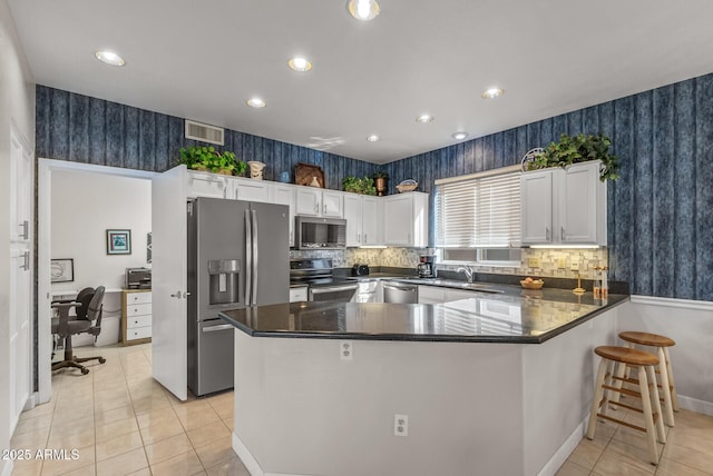 kitchen with light tile patterned floors, sink, appliances with stainless steel finishes, white cabinetry, and kitchen peninsula