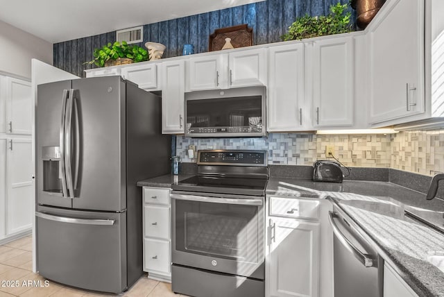 kitchen featuring backsplash, stainless steel appliances, light tile patterned floors, and white cabinets