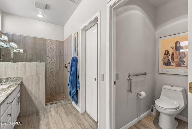 bathroom with tiled shower, vanity, and toilet