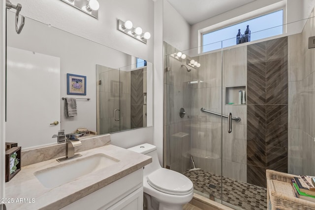 bathroom featuring vanity, a shower with shower door, and toilet