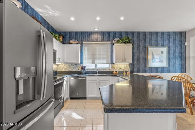 kitchen featuring light tile patterned flooring, appliances with stainless steel finishes, sink, white cabinets, and backsplash