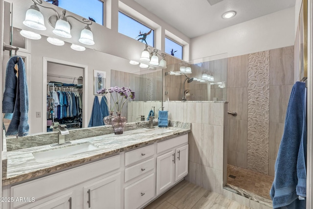 bathroom with tiled shower and vanity