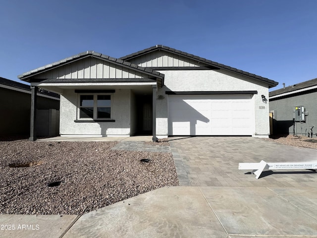 ranch-style home with a garage, a tiled roof, decorative driveway, and stucco siding