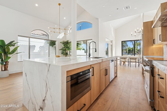 kitchen featuring a large island, stainless steel appliances, high vaulted ceiling, a chandelier, and decorative light fixtures