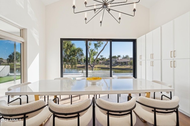 dining area with hardwood / wood-style floors, a water view, and high vaulted ceiling