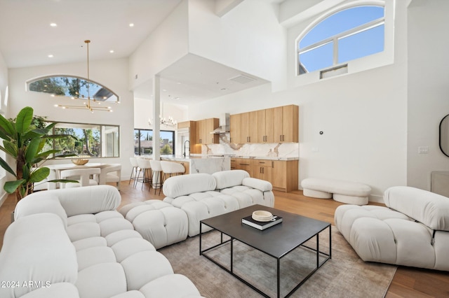 living room featuring light wood-type flooring, high vaulted ceiling, and a notable chandelier