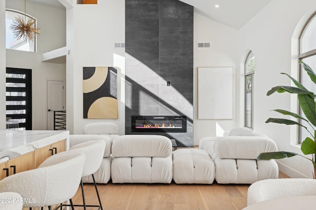 living room featuring a fireplace, light wood-type flooring, and high vaulted ceiling