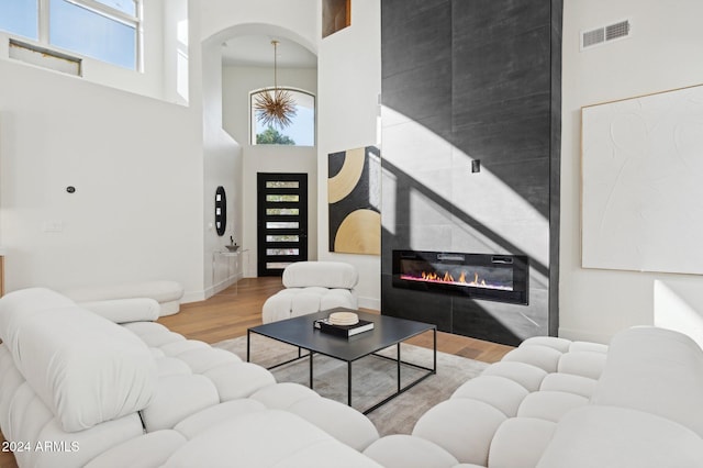 living room featuring a large fireplace, wood-type flooring, and a high ceiling