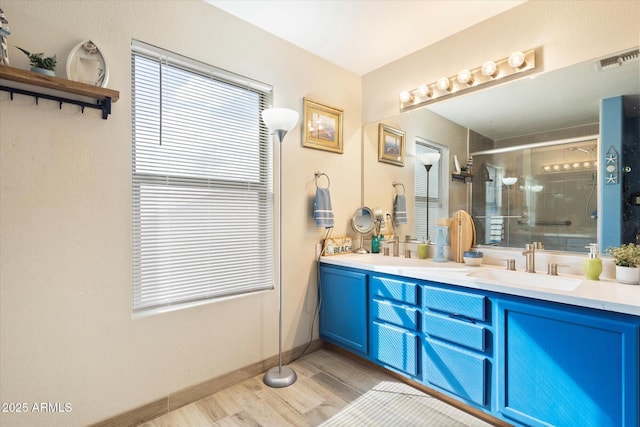 full bath with wood finished floors, visible vents, double vanity, a sink, and a shower stall