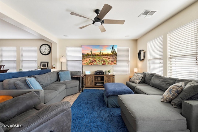 living area featuring light tile patterned flooring, visible vents, a healthy amount of sunlight, and ceiling fan