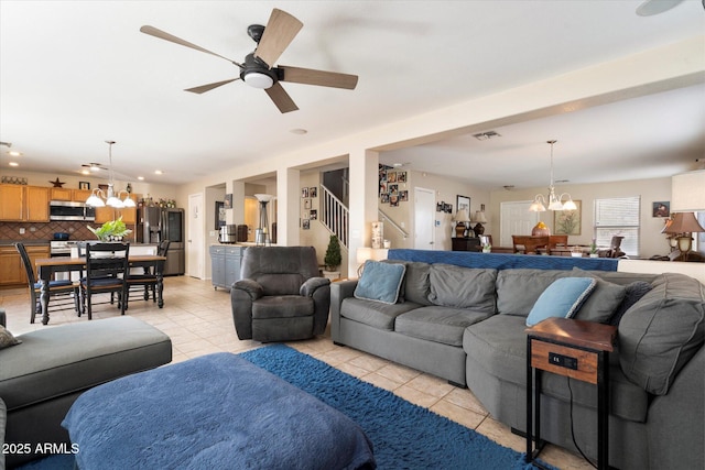 living area with light tile patterned floors, visible vents, stairs, and ceiling fan with notable chandelier