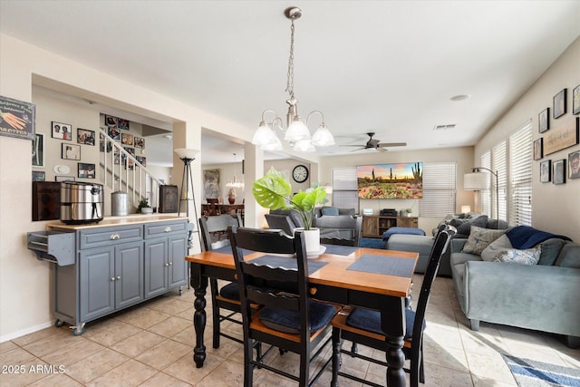 dining area with light tile patterned flooring, visible vents, ceiling fan with notable chandelier, and stairway