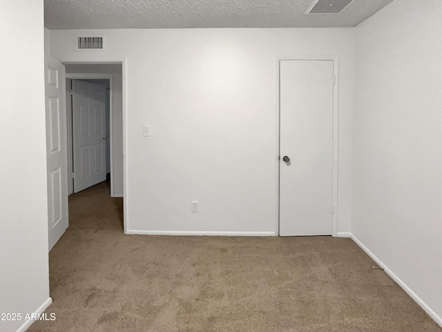 spare room with light carpet and a textured ceiling