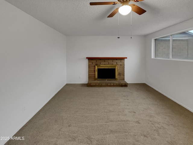 unfurnished living room featuring ceiling fan, carpet floors, a textured ceiling, and a brick fireplace