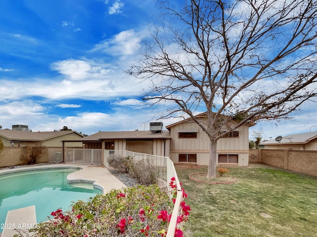 back of property featuring a fenced in pool and a yard