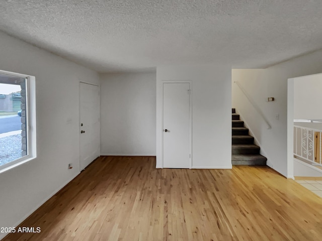 unfurnished room with a textured ceiling and light hardwood / wood-style floors