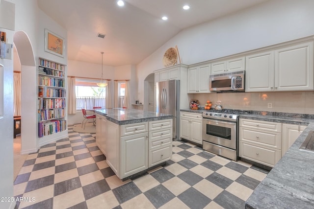 kitchen with visible vents, a center island, light floors, appliances with stainless steel finishes, and arched walkways