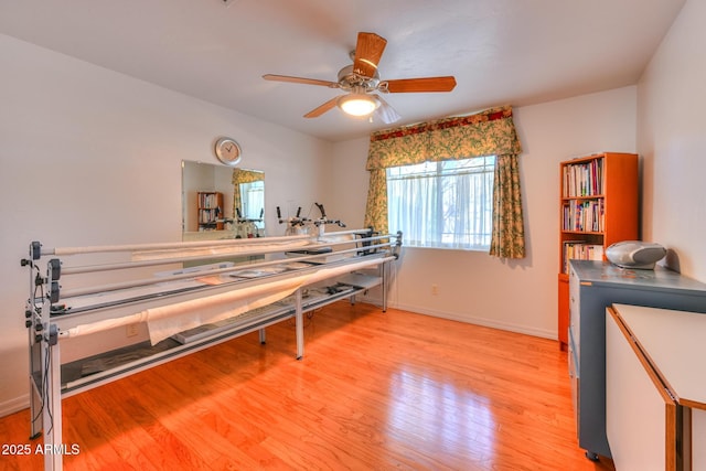 interior space with a ceiling fan, light wood-type flooring, and baseboards