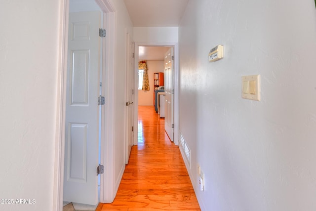 corridor with light wood-style flooring and baseboards