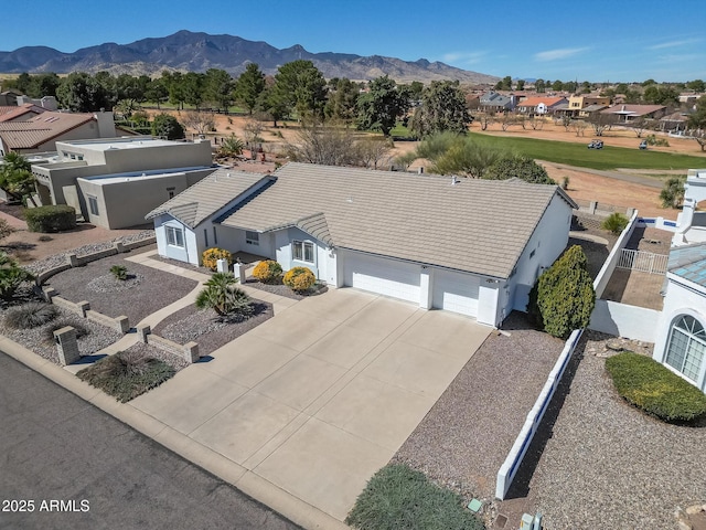 view of front of home with fence, stucco siding, driveway, a garage, and a mountain view