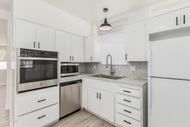 kitchen featuring sink, white cabinets, hanging light fixtures, and appliances with stainless steel finishes